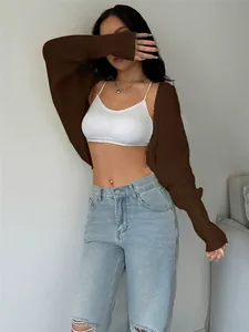 Loose short brown knitted shrug cardigan worn over white bra and light blue jeans