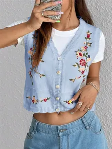 Détail du débardeur en tricot bleu clair avec broderies florales colorées et col en V