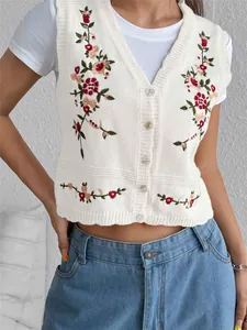 Vue détaillée d'un gilet en maille blanc avec broderie florale colorée sur un mannequin femme
