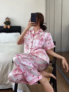Women's pink striped pajama set with red bow prints shown in a bedroom setting