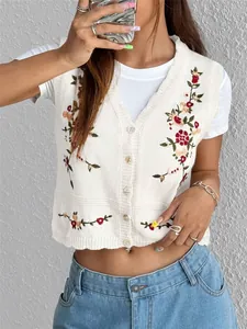 Détail de près d'un gilet blanc en maille tricoté avec broderies de fleurs