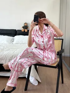 Full body shot of a pink striped pajama set with bows and heart patterns in a cozy bedroom
