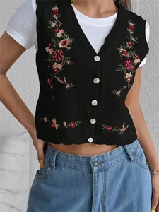 Gros plan montrant la broderie florale complexe et les boutons blancs sur le gilet en tricot noir
