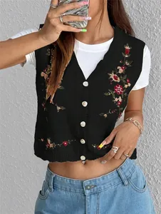 Détail rapproché d'un gilet en tricot noir avec une broderie florale très délicate.