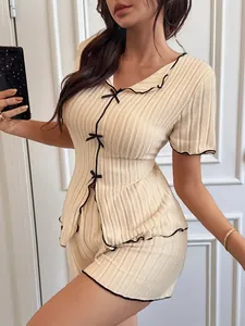 Detail view of cream ribbed pajama set with elegant black bows and contrast trim