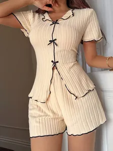 Elegant two-piece beige ribbed pajama set featuring black bow accents and stylish ruffle trim