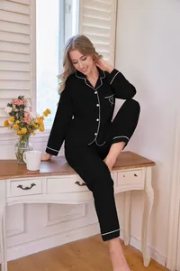 Elegante Frau im schwarzen zweiteiligen Pyjama-Set mit Herzstickerei und weißer Paspelierung