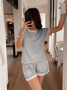 Modella indossa un set casual con top a righe a maniche corte e pantaloncini coordinati