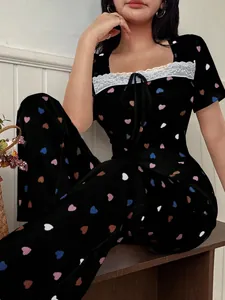 Detailed view of women's black pajama set with colorful heart print and lace trim.