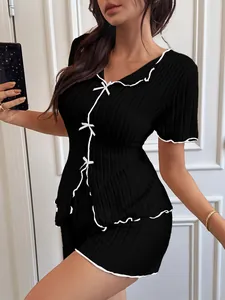 Detailed view of women's black ribbed pajama set with white lettuce trim and bow accents