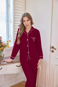 Detail einer Frau in einem weinroten Pyjama-Set mit Herzstickerei und langen Ärmeln.