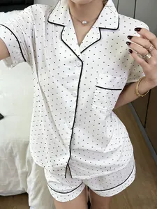 Detailansicht des weißen Polka-Dot-Pyjama-Sets für Damen mit schwarzer Paspelierung