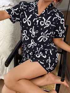 Detailansicht eines schwarzen Damen-Pyjama-Sets mit weißen Schleifen- und Sternmustern