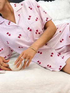 Detail of women's pink striped pajama set with red heart print and short sleeves