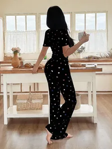 Back view of a woman wearing a black heart-patterned pajama set in a cozy kitchen setting