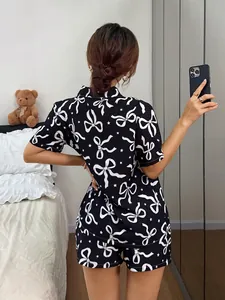 Rückansicht eines schwarzen Damen-Pyjama-Sets mit weißem Schleifenmuster im Schlafzimmer