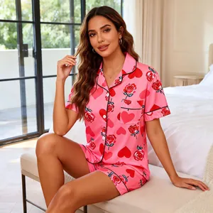 Women's pink short sleeve pajama set with rose and heart prints in bedroom setting