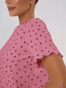 Close-up detail of pink cotton pajama top with red heart print and ruffle sleeve trim