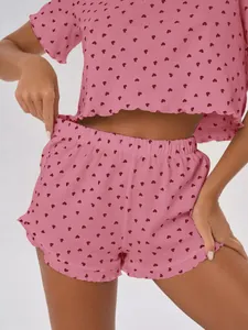 Detail of pink pajama set with red heart prints and delicate lettuce edge hem design.