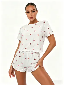 Detail view of woman wearing white cotton pajama set with cherry print and lettuce trim