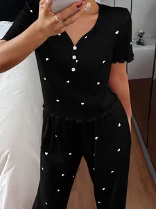 Detailed view of women's black ribbed pajama set with white heart print and button neck