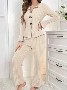 Detail of beige ribbed two-piece pajama set with bow accents and contrast piping