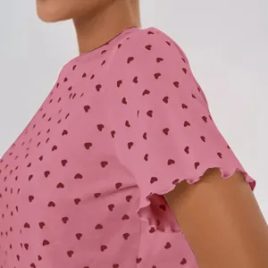 Close-up view of a pink short sleeve pajama top featuring red heart print and ruffle hem