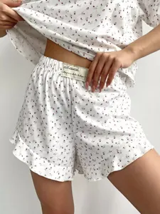 Detail van gebloemde katoenen pyjamaset met shorts met ruches en elastiek.