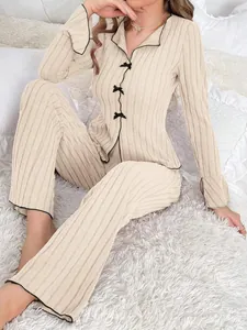 Elegant beige ribbed pajama set for women featuring decorative black bows and piping accents
