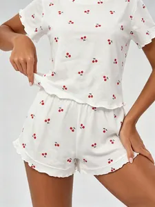 Close-up detail of white 100% cotton pajama set with red cherry print and ruffles.