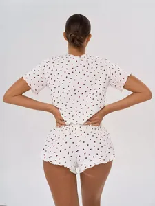 Rear view of a white two-piece cotton pajama set featuring red heart prints and ruffled hem