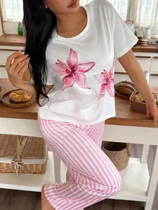 Μοντέλο με λευκό φλοράλ T-shirt και ροζ ριγέ παντελόνι πιτζάμας στην κουζίνα