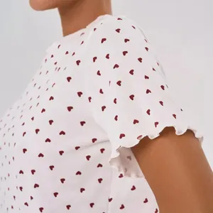 Close-up of women's white 100% cotton pajama top featuring red heart prints and frilly sleeves