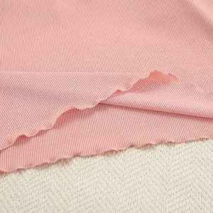 Close-up of pink ribbed knit fabric featuring a delicate wavy lettuce trim hem
