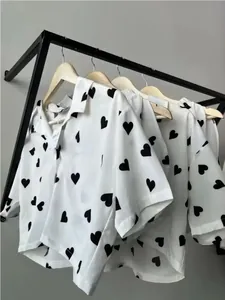 Close-up detail of white women's pajama set featuring black heart prints on a clothing rack