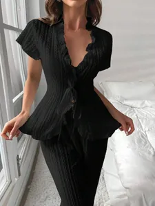 Dettaglio del completo loungewear nero in maglia con cardigan a balze e pantaloni coordinati