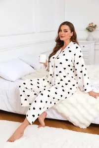 Comfortable plus size white pajama set with black heart prints worn by a woman on a bed.