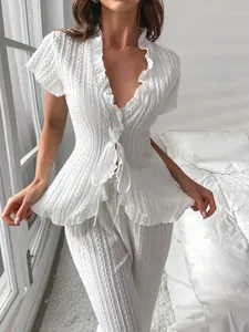 Dettaglio dell'elegante set da casa in maglia bianca con volant e cardigan con laccetti