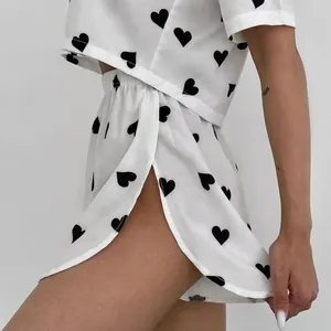 White two-piece pajama set featuring black heart print crop top and side-split shorts.