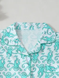 Detailaufnahme eines weißen Schlafanzugkragens mit mintgrünem Affen-Print und Borte.