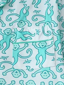 Nahaufnahme des blaugrünen Affen-Prints auf weißem Pyjama-Stoff mit Taschenpaspelierung