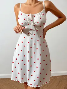 Close-up detail of a white spaghetti strap dress with red heart prints and a front bow tie