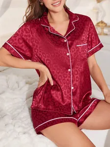 Details des bordeauxroten Satin-Pyjama-Sets mit Leopardenmuster und weißem Kontrastbesatz.
