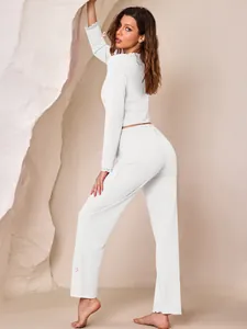 Close-up detail of white ribbed lounge set showing lace cuffs and pink bow accents.