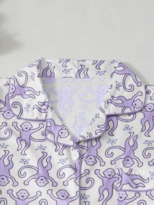 Detail des Damen-Pyjama-Oberteils mit lila Comic-Affen-Print und Paspelierung.