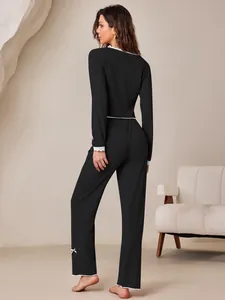 Detailed view of black ribbed pajama set with white lace trim and pink bows.