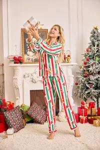 Femme en pyjama de Noël rayé avec motifs de pain d'épices dans un intérieur douillet