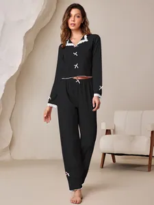 Elegant black two-piece pajama set featuring delicate lace trim and pink bow accents for women.