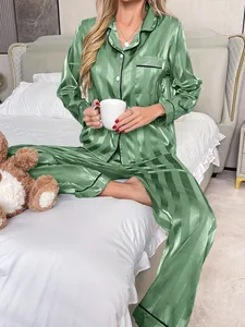 Ensemble de pyjama en satin à rayures vertes avec col à revers et boutons sur un lit.