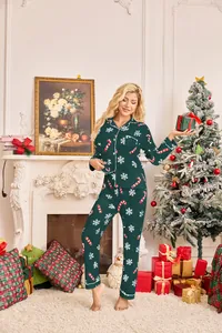 Woman wearing a dark green Christmas pajama set with snowflake print by a fireplace